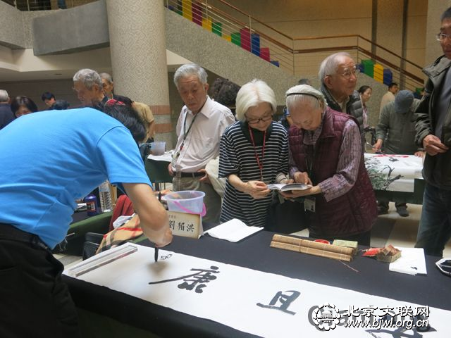 6 第十六届京味文化之旅走进长庚养生文化村，书画家进行笔会交流，一对母女观看书法创作。千龙网记者纪敬摄