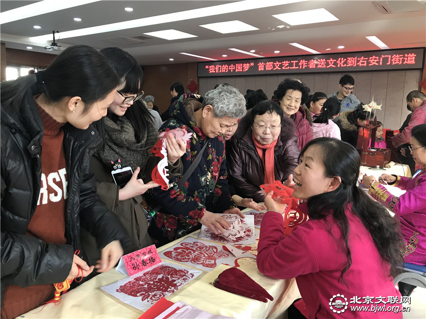 孙春播老师一边赠送居民窗花一边解答居民剪纸方面的问题