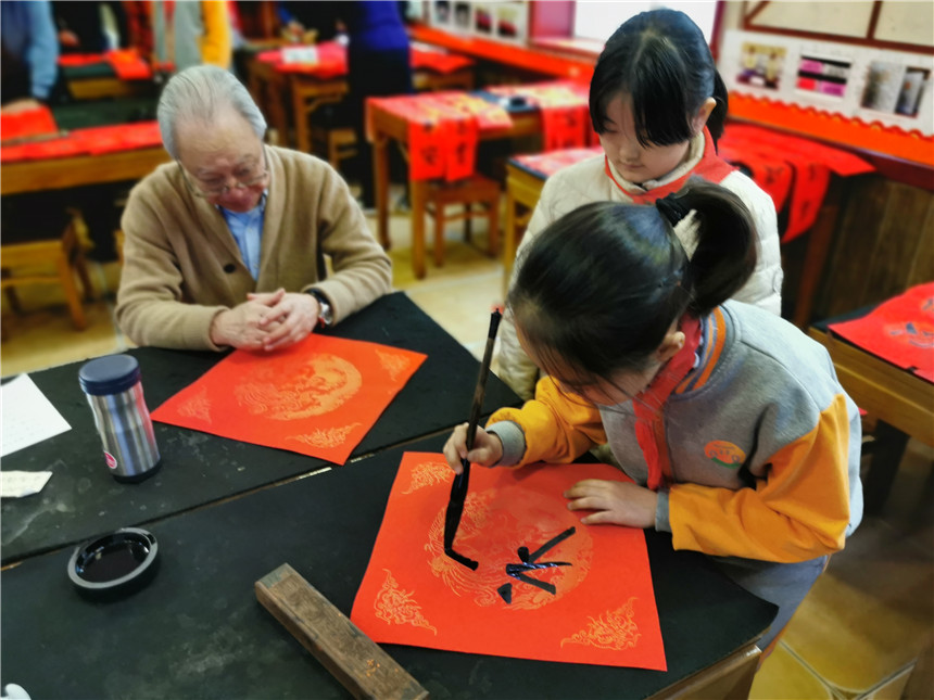 03 小学生在书法家的指导下提笔写“福”