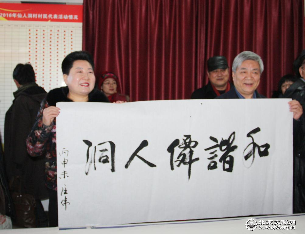 民盟中央副主席龙庄伟（右）向仙人洞村党支部书记张立英（左）赠送“和谐仙人洞”书法作品